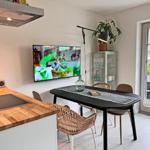 Küche mit Essbereich, Fernseher an der Wand und Terrasse mit Sitzgelegenheit.