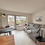 Wohn- und Essbereich mit Sofa, Tisch und Blick auf Balkon.