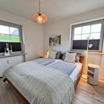 Schlafzimmer mit Doppelbett, zwei Fenstern und Deckenleuchte.