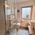 Badezimmer mit Dusche, Toilette und Waschbecken mit Fenster