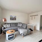 Wohnzimmer mit grauem Sofa, runden Tisch und Stehlampe.