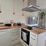 Küche mit Holzoberflächen, weißen Schränken und integriertem Herd.