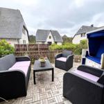 Terrasse mit Sitzgruppe, Liegestuhl und Gartenzaun.