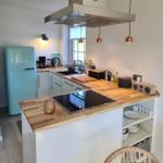 Küche mit Holz Arbeitsplatte, Edelstahl Dunstabzug und hellen Wänden.