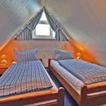 Zwei Einzelbetten unter Dachschrägen mit Nachttischen und Lampe.