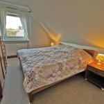 Schlafzimmer mit Dachschrägen, Bett, Nachttisch und Fenster.