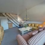 Wohnbereich mit Sofa, Tisch und Stufen zur Küche.