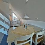 Essbereich mit Tisch, Stühlen und Blick in die Küche.