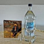 Ein Buch und eine Flasche mit zwei Gläsern auf einem Tisch.