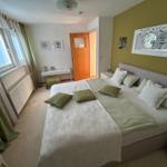 Schlafzimmer mit Doppelbett, grünen Kissen und Fenster mit Vorhängen.