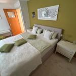 Schlafzimmer mit Bett, Nachttischen und grüner Wand.