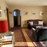 Wohnzimmer mit Ledersofa, Sessel, Teppichen und Wandbildern.