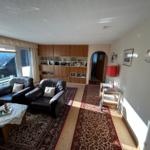 Wohnzimmer mit zwei Sesseln, Teppich und Bücherregal.