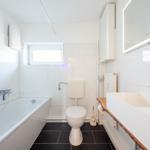 Badezimmer mit Badewanne, Toilette und Waschbecken mit Spiegel.