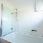 Badezimmer mit Badewanne und Duschkabine, Wandheizung und Fenster