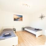 Zwei Einzelbetten, Wandbild und Kompass an der Wand