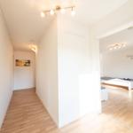 Flur mit Holzboden und Schlafzimmer mit Bett und Wanddekoration.