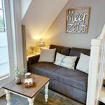 Ein Sofa mit Kissen unter einem Dachfenster neben einer Treppe.