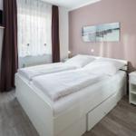 Schlafzimmer mit Doppelbett, Nachttisch und Fenster mit Vorhängen.
