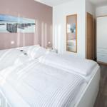 Schlafzimmer mit Doppelbett, Kleiderschrank und Wandbild.