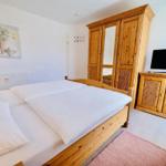 Schlafzimmer mit Bett, Kleiderschrank und TV