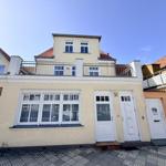 Haus mit Balkon und weißen Fenstern. Hausnummer 30. Terrakottadach.