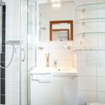 Badezimmer mit Dusche, Waschbecken und Spiegel