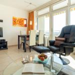 Wohnzimmer mit Essbereich, TV, Sessel und Glas-Tisch
