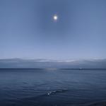 Mond über ruhigem Meer, kleines Boot im Hintergrund