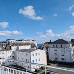 Blick von Balkon auf Wohnhäuser und Himmel mit weißen Wolken.