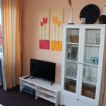 Wohnzimmer mit Fernseher, Glasvitrine und Fenster zur Terrasse.