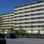 Hochhaus mit Balkonen und Parkplatz vorne
