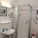 Badezimmer mit Dusche, Waschbecken und Spiegel