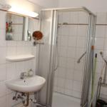 Badezimmer mit Dusche, Waschbecken und Spiegel