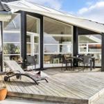 Terrasse mit Liegestuhl und Esstisch unter großem Glasbereich.