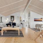 Wohn- und Essbereich mit Holzdecke, Sofa, Tisch und Stühlen.
