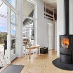 Ein Raum mit Holzboden, Kamin und großem Fenster zum Balkon.