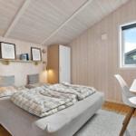 Schlafzimmer mit Bett, Schreibtisch und Fenster. Holzwände und Decke.