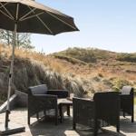 Terrasse mit Sitzgruppe und Sonnenschirm. Blick auf Dünenlandschaft.