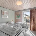 Schlafzimmer mit Doppelbett, Fenster und Vorhang.