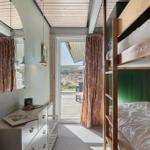 Schlafzimmer mit Doppelstockbetten, Schrank und Fenster zur Terrasse.