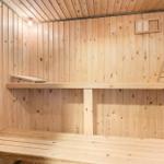 Holzsauna mit mehreren Sitzbänken und einer Wandöffnung.
