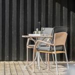 Terrasse mit Tisch und zwei Stühlen vor schwarzem Holzhaus