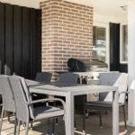 Terrasse mit Tisch, Stühlen und Grill an der Hauswand.