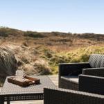 Terrasse mit Gartenmöbeln und Blick auf Dünenlandschaft.
