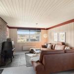 Wohnzimmer mit braunem Sofa, Kamin und Fensterblick