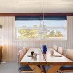 Esszimmer mit Holztisch, Stühlen und Fensterblick auf Bäume
