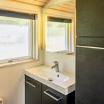 Badezimmer mit Waschbecken, Spiegel und Fenster.