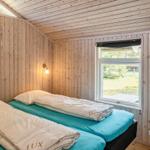 Zwei Betten mit hellblauen Matratzen und weißen Bettwäschen in einem Holzraum mit Fenster.