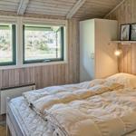 Schlafzimmer mit Bett, Fenstern und Holzwand.
